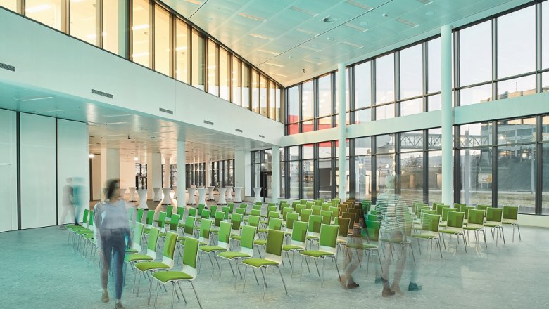 Modern conference room with green chairs and large windows in the Vienna Airport Conference & Innovation Center.
