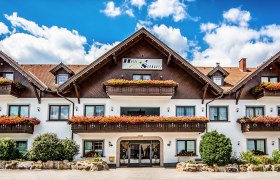 A traditional hotel with wooden balconies and flower boxes against a blue sky.