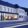 Exterior view of the Gasthof Hotel Zur Schonenburg at dusk with illuminated windows and passing cars.