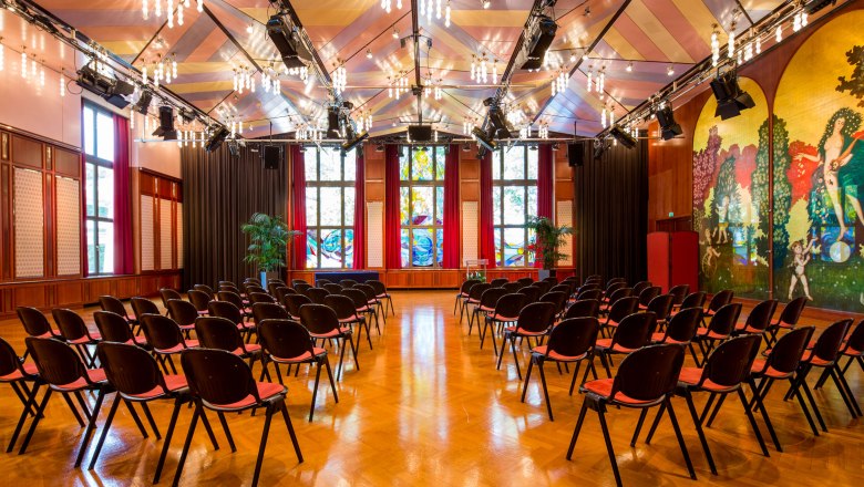 Interior view of the Casineum in the Congress Center Baden with rows of chairs and colorful wall decorations.