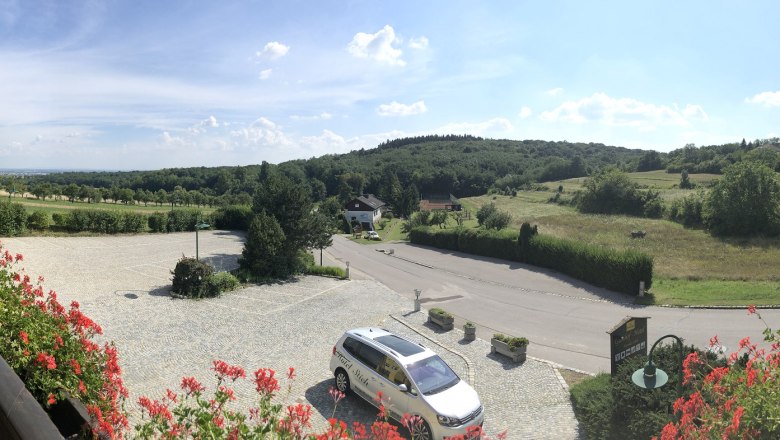 Panoramic view of a rural landscape with hills and meadows from a hotel balcony.