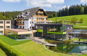 Hotel Schwarz Alm with modern design, surrounded by green landscape and forest.