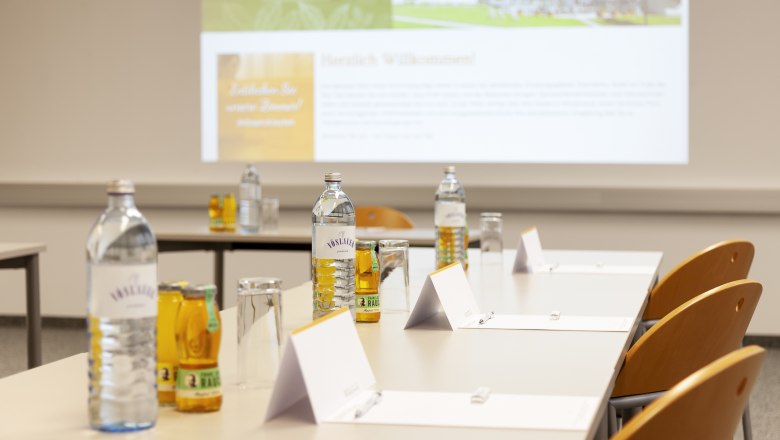 Seminar room with tables, chairs, water bottles and notepads.