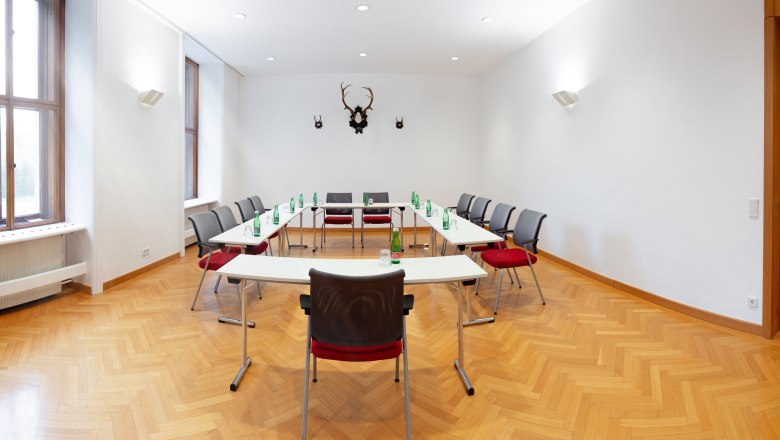Seminar room with U-shaped table arrangement, chairs and water bottles.