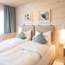 Cozy double room with two single beds, wooden walls and modern decoration.