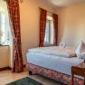 Cozy hotel room with double bed, red curtains and decorative heart-shaped towel.