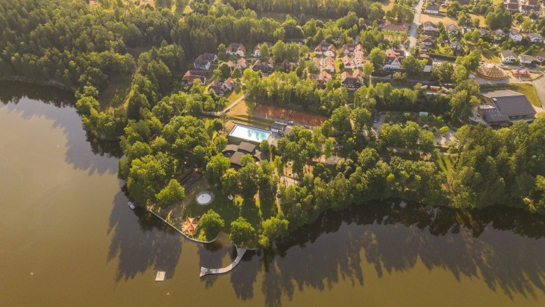 Aerial view of a vacation and theater villa by the lake with trees and buildings.