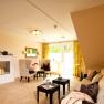 A cozy wellness relaxation area with fireplace, armchairs, sofa and small table, decorated with candles and plants.