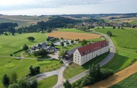Aerial view of a country estate with golf course, fields and buildings in a rural setting.
