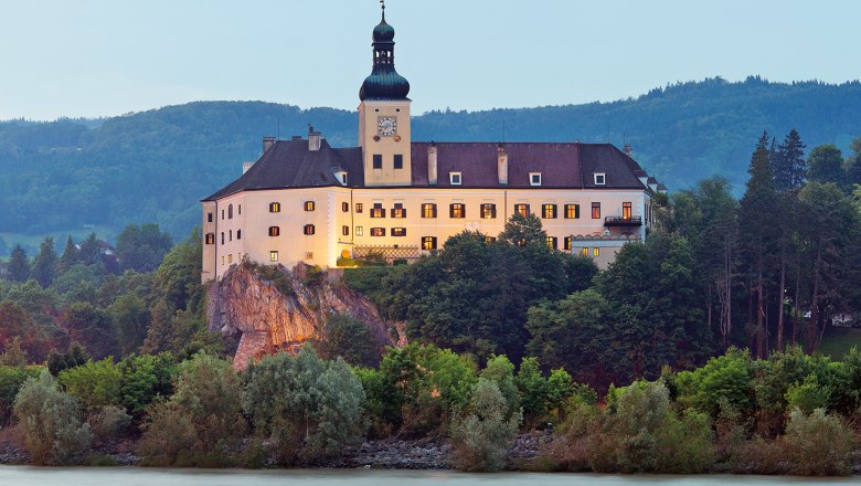 Persenbeug Castle on a hill with a river in the foreground.