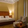 Elegant double room with a large bed, two armchairs and a table with a candle.