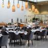 Interior view of a stylish restaurant with laid tables and hanging lamps.