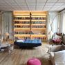 Cozy library with a large, illuminated bookshelf, armchairs and a person reading.