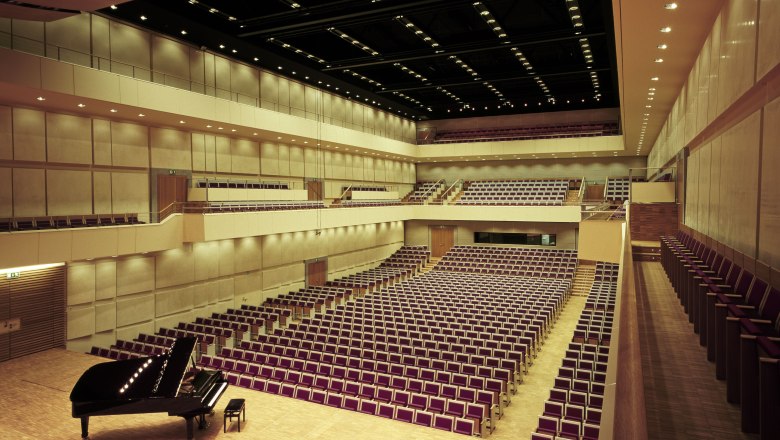 Interior view of the auditorium in Grafenegg Castle with empty rows of seats and a grand piano on the stage.