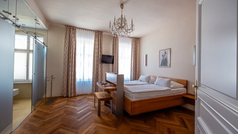 Elegant hotel room with double bed, parquet floor and chandelier.