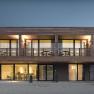Modern two-story house with wood paneling and large windows with night lighting.