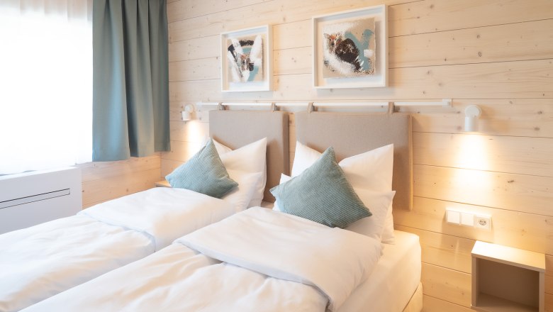 Cozy double room with two single beds, wooden walls and modern decoration.