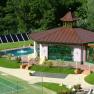 Exterior view of a wellness area with pool and pavilion surrounded by greenery.