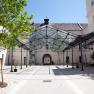 Inner courtyard with glass roof and trees, surrounded by buildings.
