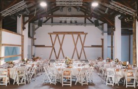 Interior view of a stylishly decorated event hall with round tables and white chairs.