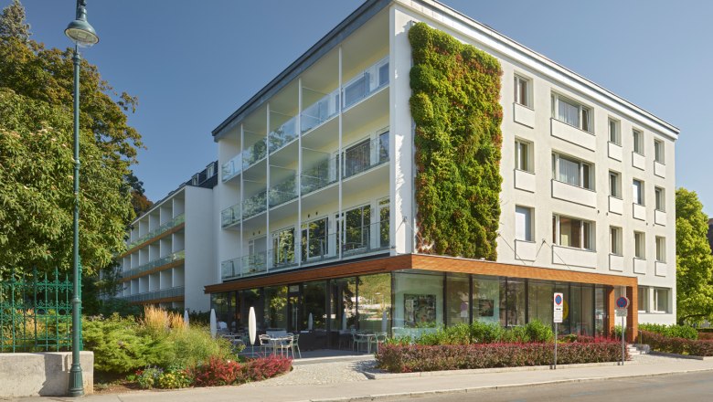 Modern building exterior with vertical garden and glass balconies in daylight.