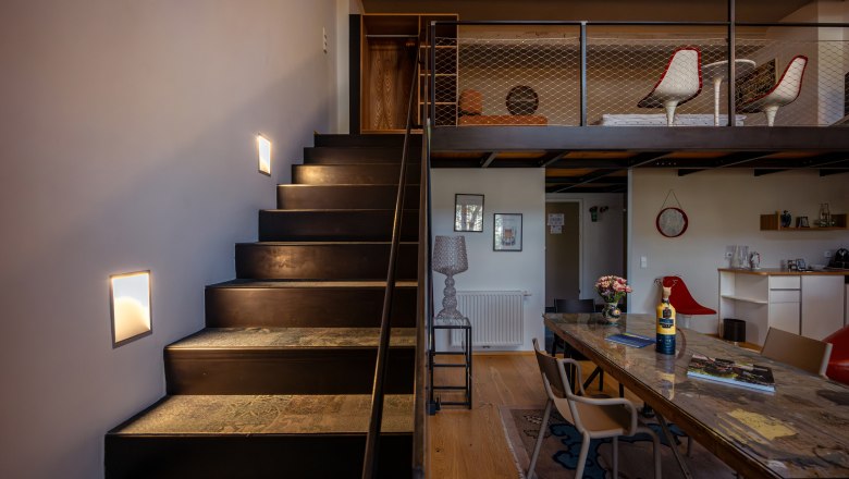 Interior view of a modern hotel room with stairs, table and chairs.