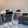 A seminar room with water carafes, glasses and a folder on a table.