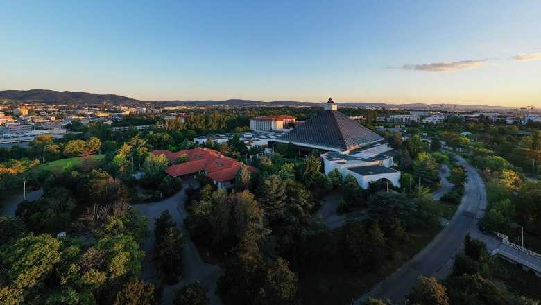 Aerial view of the Eventhotel Pyramide with surrounding landscape at sunset.
