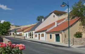 Row of colorful wine cellars in Krems, Austria, with blooming roses in the foreground.