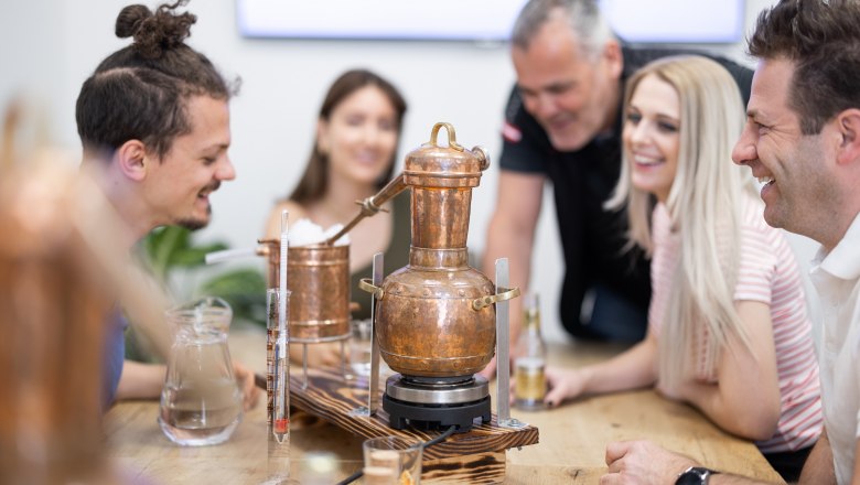 Group of people distilling schnapps with a copper still.