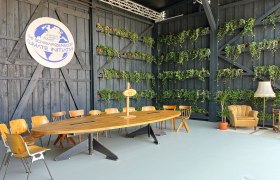 A modern meeting room with a wooden table, chairs and plants on the walls. A logo of the Schwarzenegger Climate Initiative is visible.