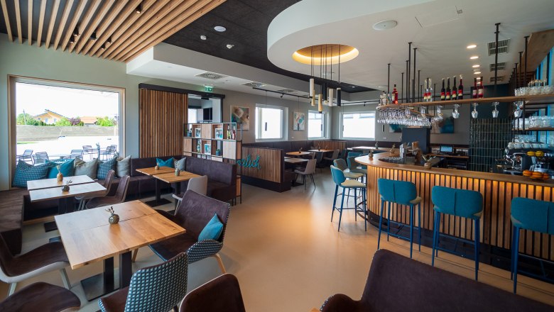 Modern bistro with wooden furniture, bar and large windows.