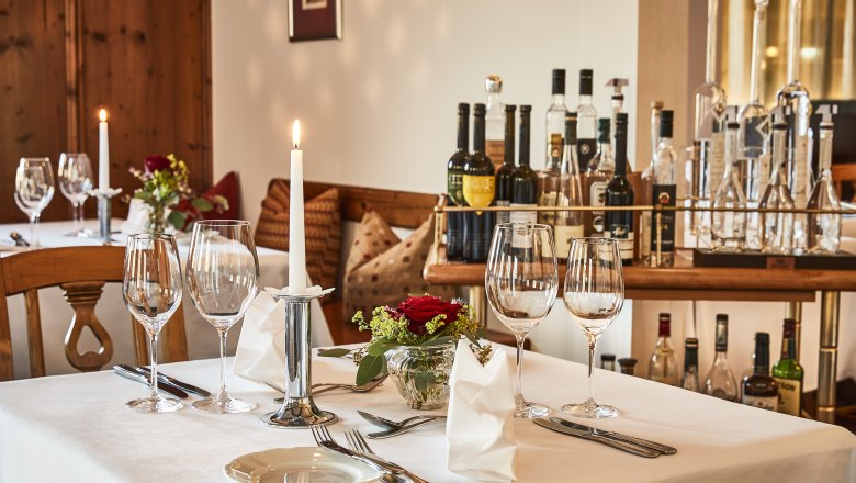 Elegant table in hotel restaurant with wine glasses, candle and flowers.