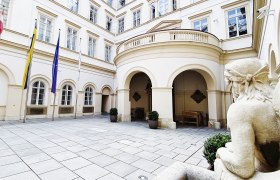 Inner courtyard of Palais Niederösterreich with flags and statue.