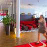 Hotel lobby with red sofa and woman with suitcase.