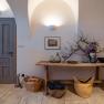 Interior with wooden table, vases, flowers and baskets. Door with inscription 'shoe room'.