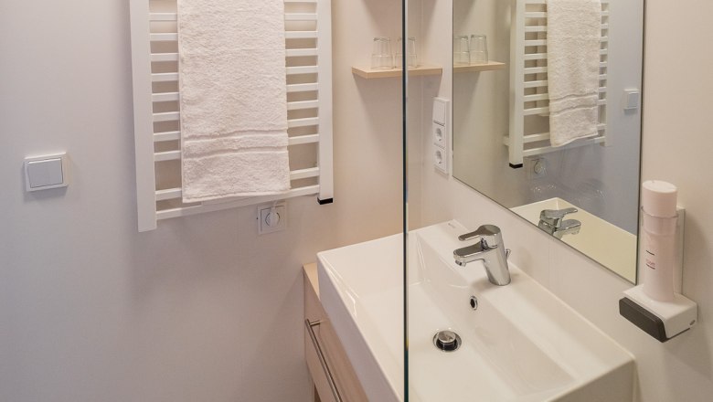 Modern bathroom with washbasin, mirror and towel rail.