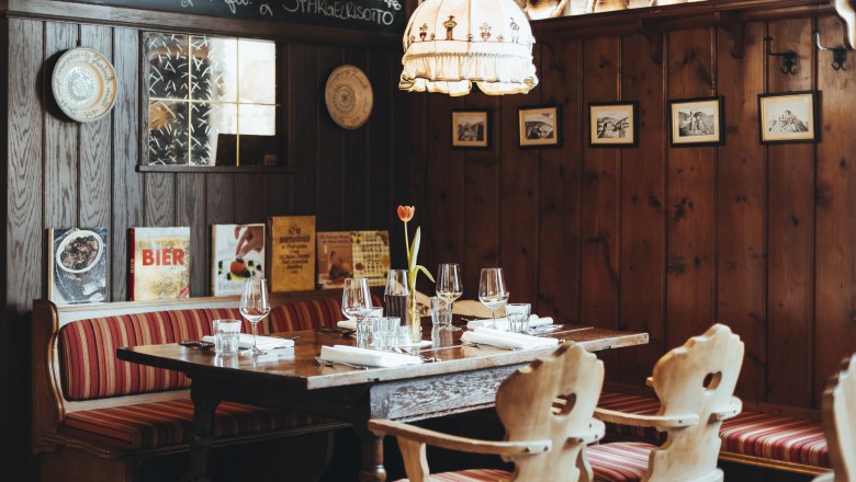 Cozy restaurant with wooden walls, red striped benches and a table setting.