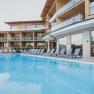 Modern hotel with pool and sun loungers outside.