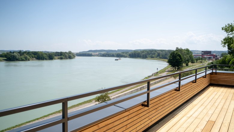 Wooden terrace with a view of a river and green landscape.