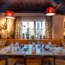 Comfortably decorated restaurant with a table setting, rustic elements and plants by the window.