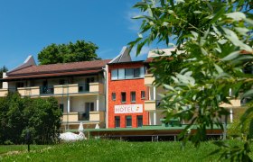 Exterior view of the Hotel-Restaurant Liebnitzm&uuml;hle with green lawn and trees in the foreground.