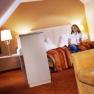 Woman sitting on a bed in a cozy hotel room with warm colors.