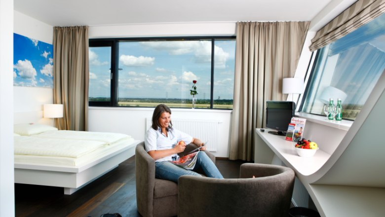 Woman sitting in a modern hotel room reading a magazine.