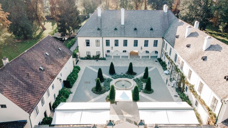 Aerial view of a historic castle with courtyard and garden.