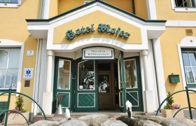 Entrance to Hotel Moser with yellow façade and green doors.