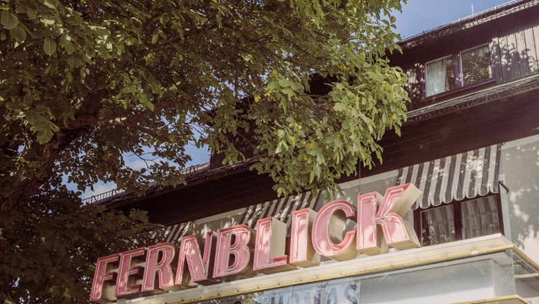 Distant view, © Matthias Kronfuss Building with the lettering 'FERNBLICK' and trees in the foreground.