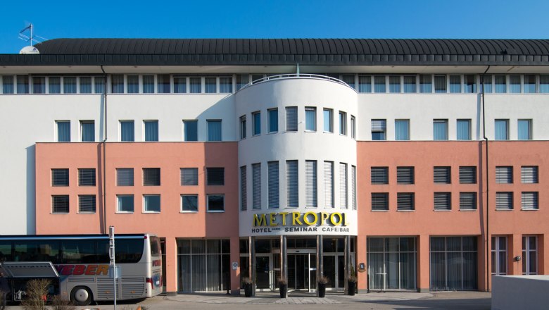Facade of the Hotel Metropol with bus in the foreground.