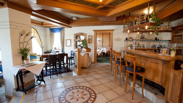 Cozy hotel bar with wooden furniture and decorative tiled floor.