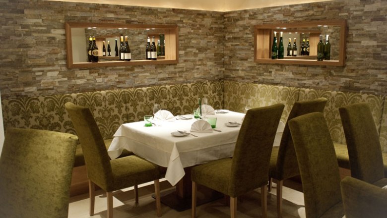 Elegant restaurant with laid table and green chairs.